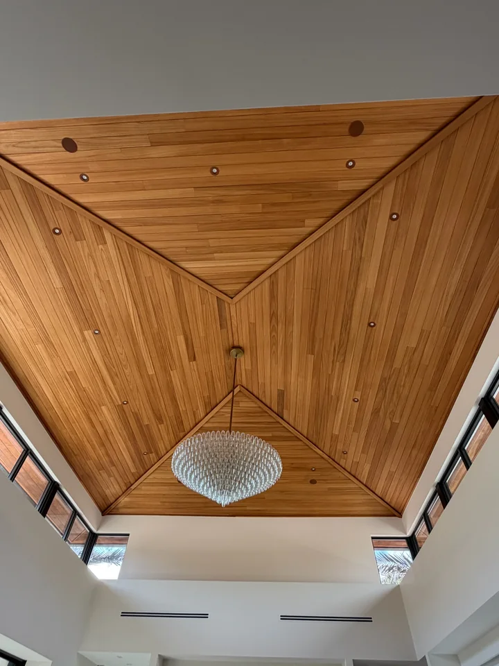 Ayous ceiling with framed sloping planes, a crystal chandelier and high windows on both sides