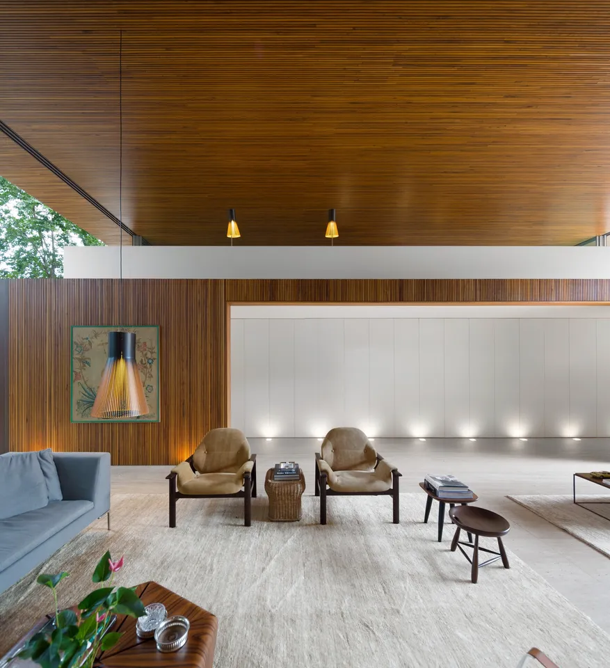 Wood ceiling above a double-height living area with lounge chairs and textured walls
