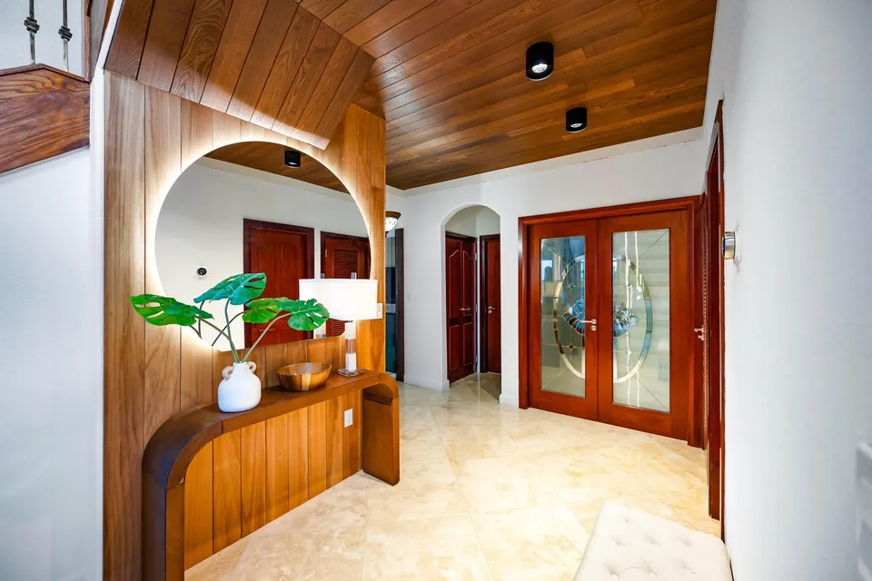 Wood-lined entry ceiling above a console and a tall arched opening