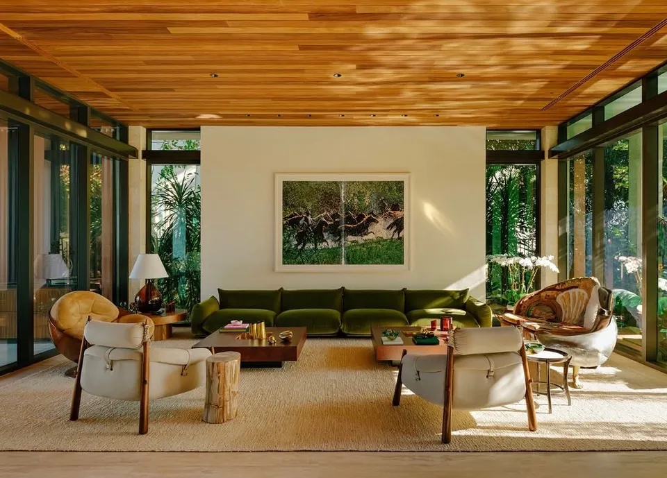 Warm wood ceiling above a finished living room with garden-facing glass walls and a green sofa