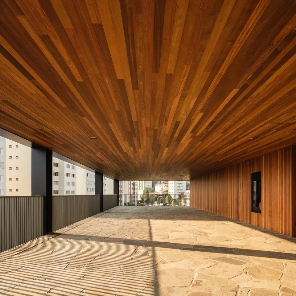 Long wood-lined ceiling seen in perspective above a sunlit architectural space