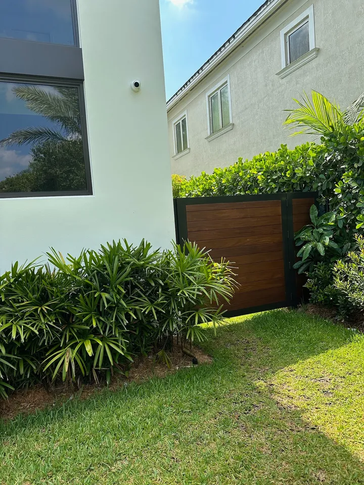 Wood garden gate between pale walls and dense green planting