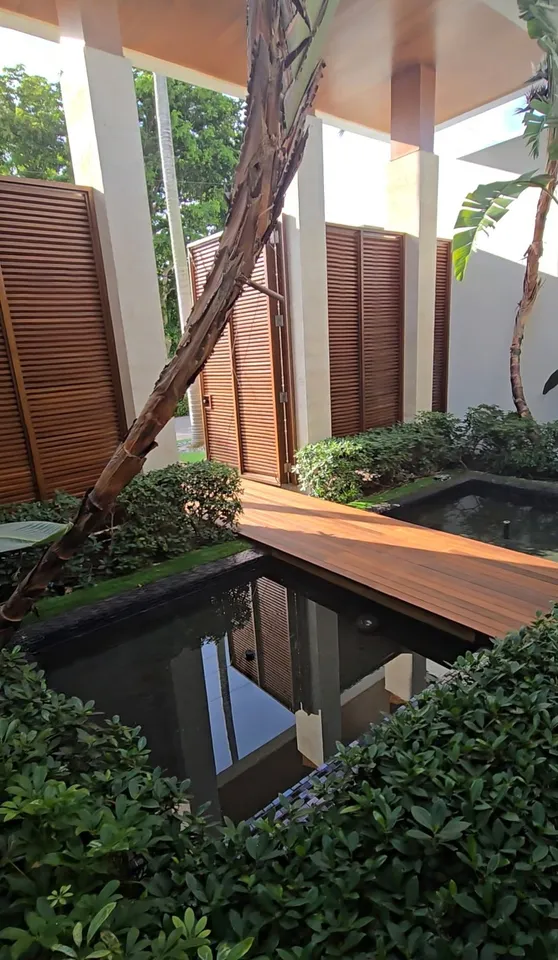 Timber privacy screening beside a shaded planted courtyard and reflecting pond