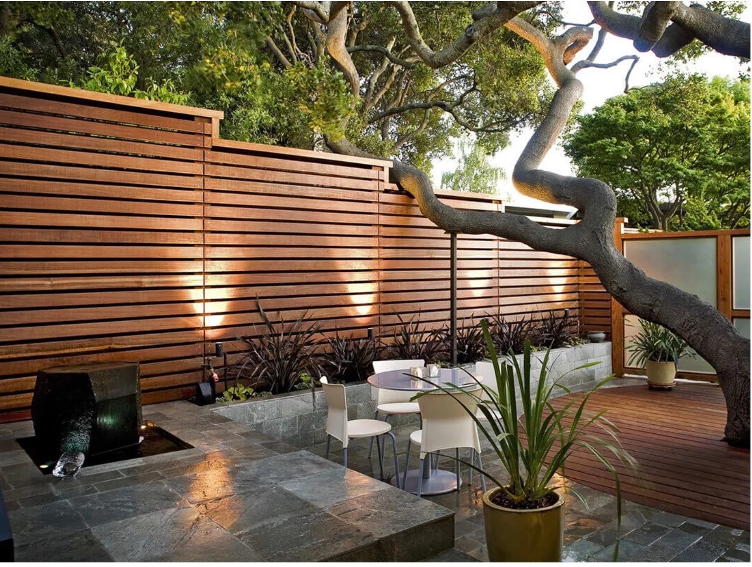 Horizontal wood privacy screen enclosing a landscaped garden seating area