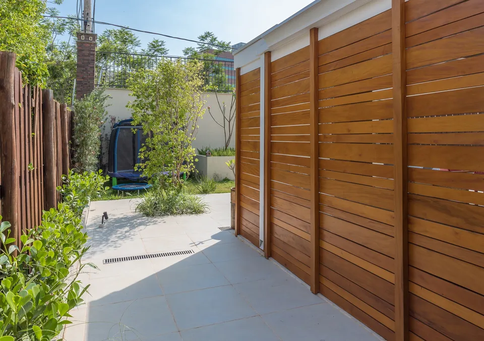 Tall horizontal timber screen beside a garden path and a planted entry