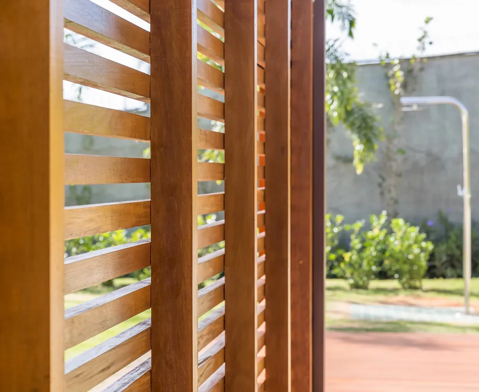 Close-up of timber louvres filtering a view toward a garden