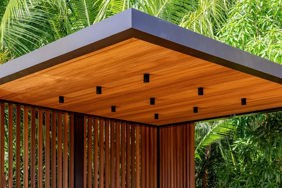 Timber-screened garden pavilion with a lined canopy and tropical planting