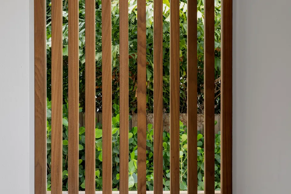Close-up of spaced vertical timber screening with greenery behind
