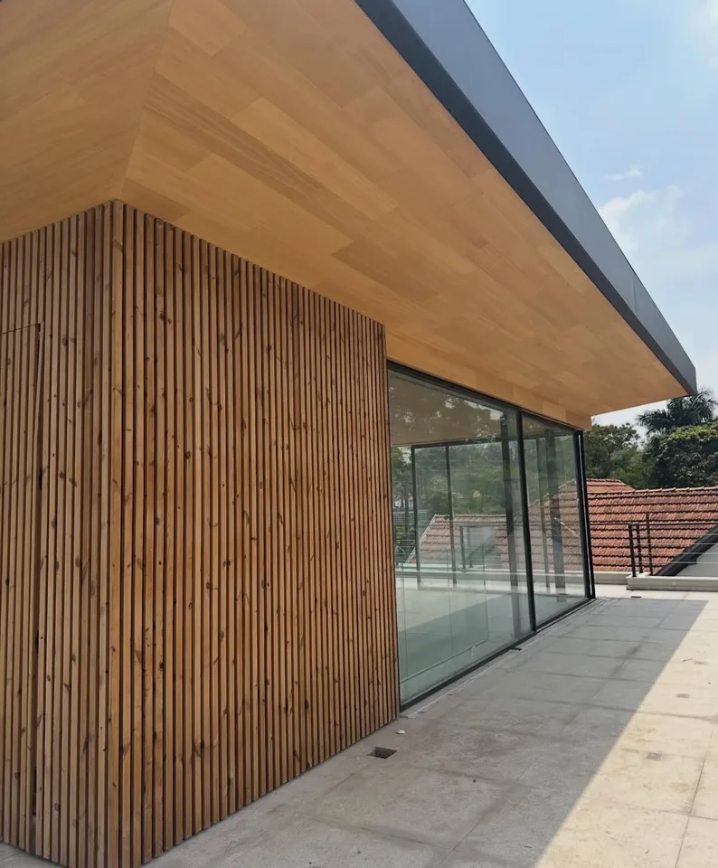 Vertical wood cladding wrapping a corner beneath a projecting roof edge