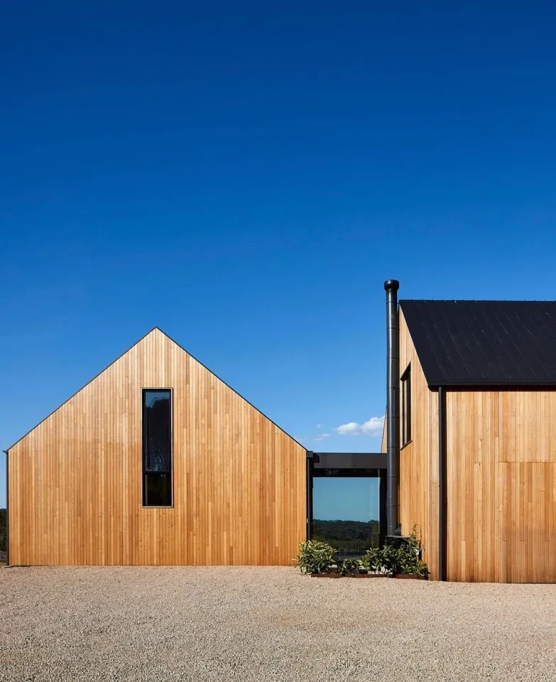 Simple gabled building with vertical wood cladding and a narrow dark window
