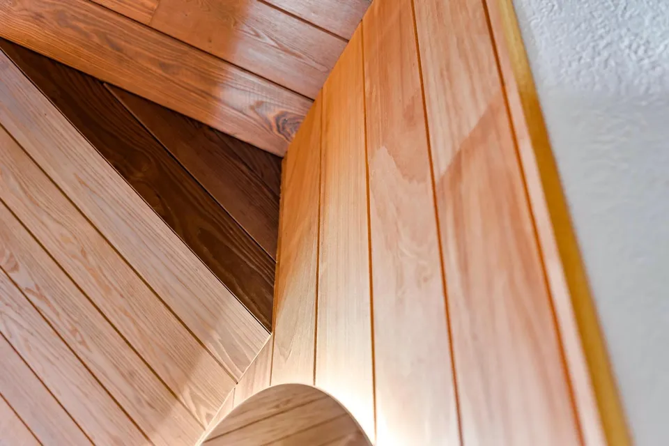 Close architectural detail of wood boards meeting a curved opening and overhead lining