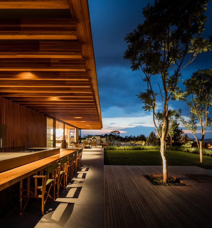 Wood-lined overhang with warm lighting beside a planted terrace at dusk