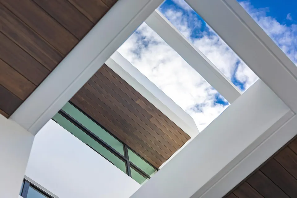 Wood-lined soffits framed by white architectural volumes and open sky
