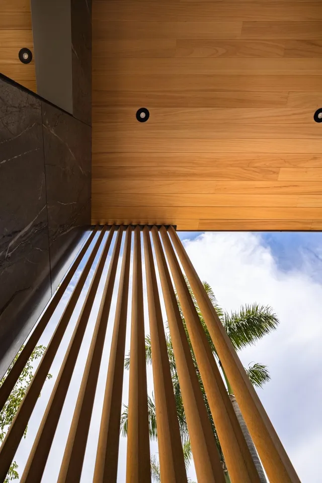 Wood soffit meeting a vertical timber screen against a blue sky