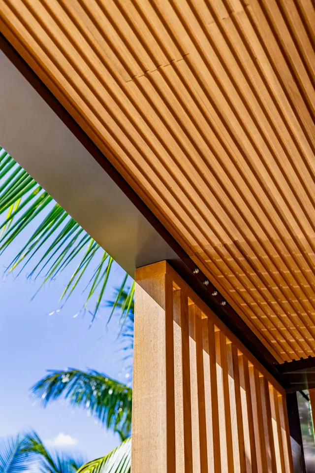 Close upward view of a finely lined wood canopy meeting a timber screen