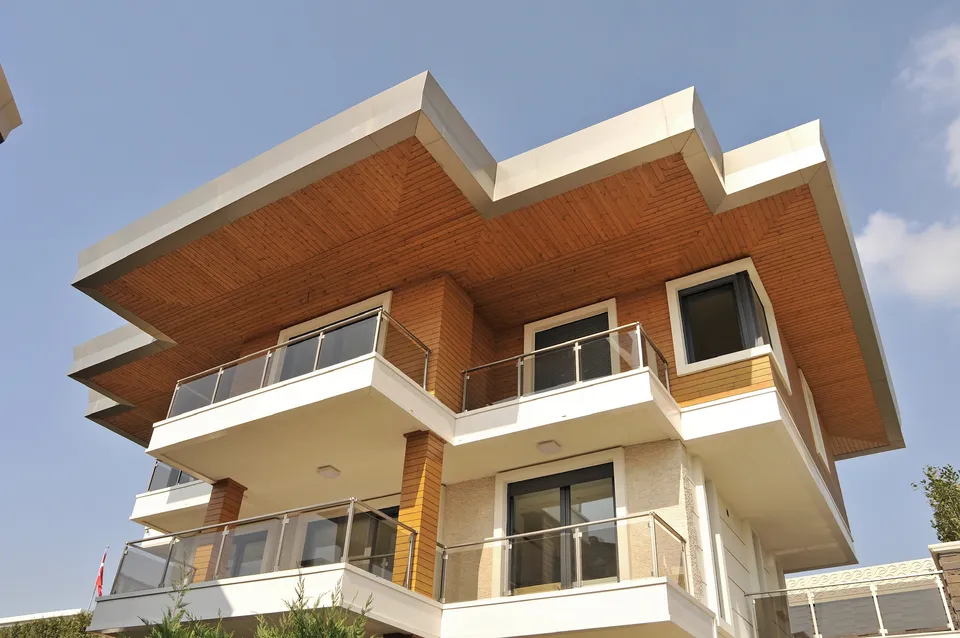 Stepped white roofline with warm wood soffits above balconies