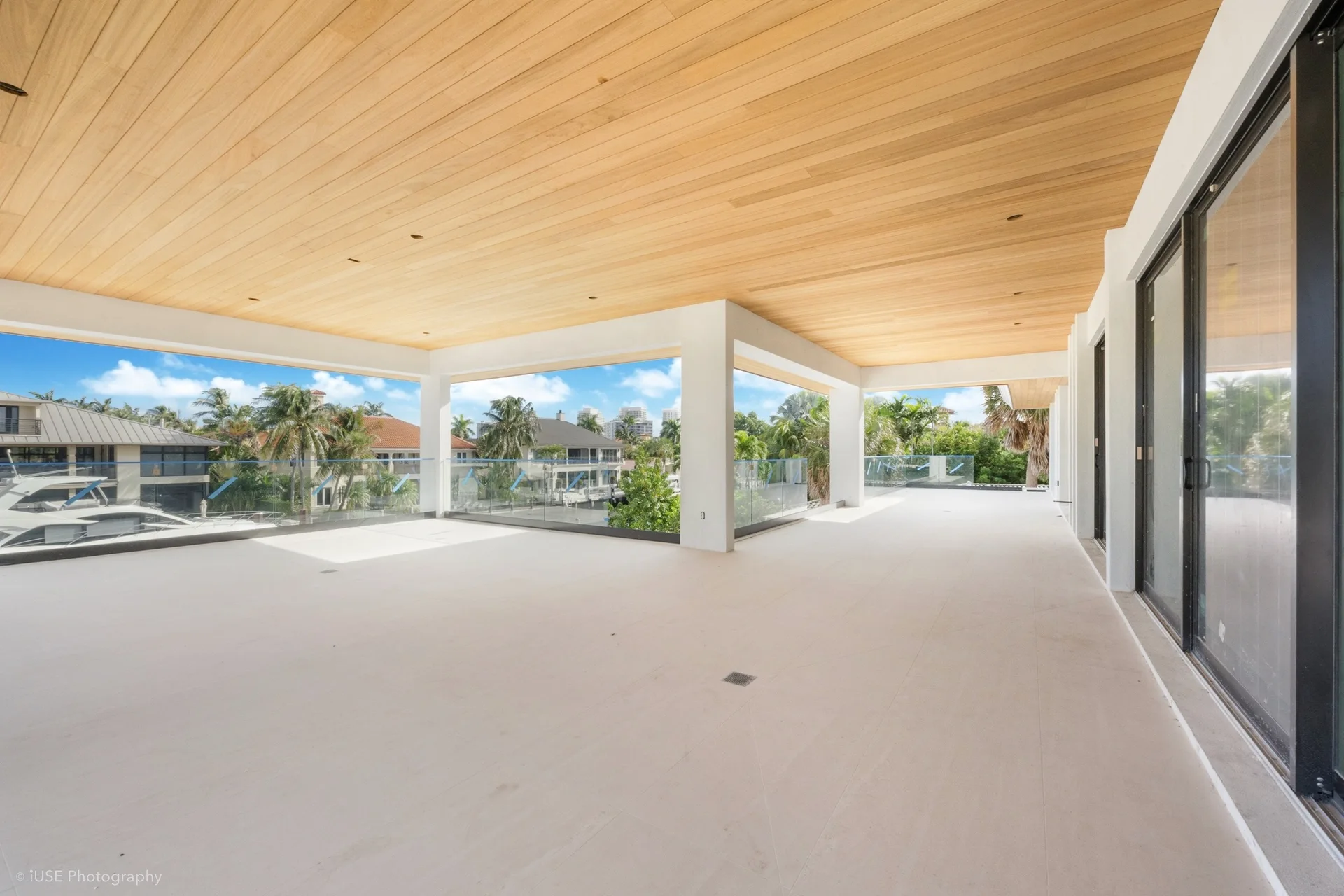 Pale wood-lined soffit above a wide waterfront veranda with white columns