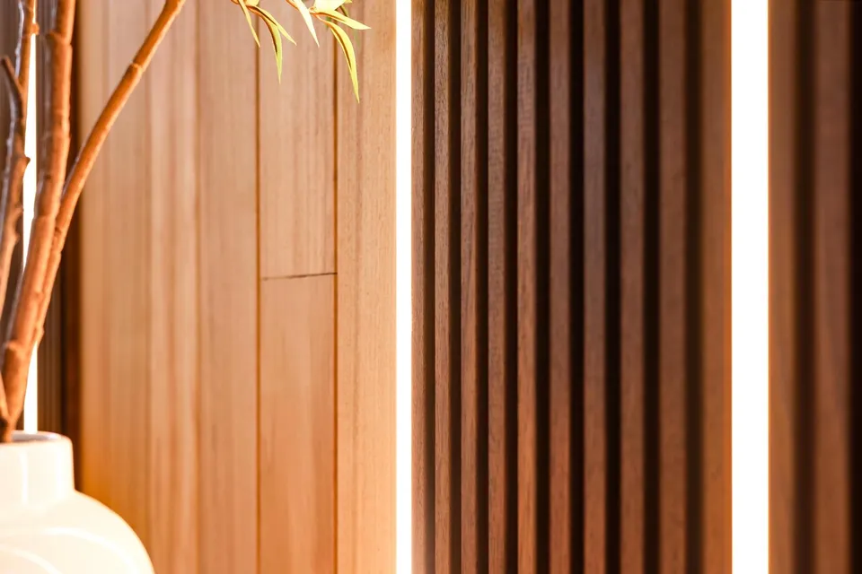 Close-up of fluted vertical wood lining beside a softly lit interior