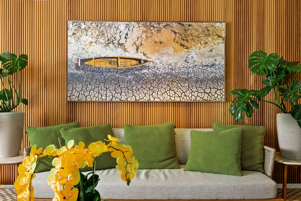 Vertical fluted wood wall behind a green sofa, artwork and indoor plants