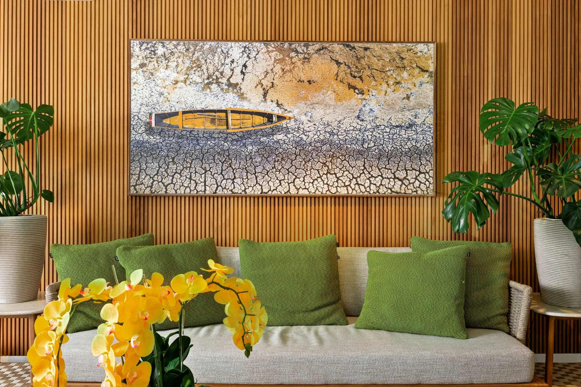 Vertical fluted wood wall behind a green sofa, artwork and indoor plants