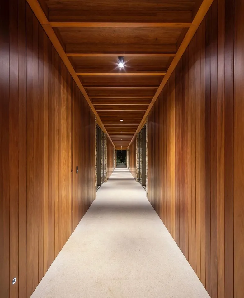 Long interior passage lined with vertical wood walls and exposed overhead beams