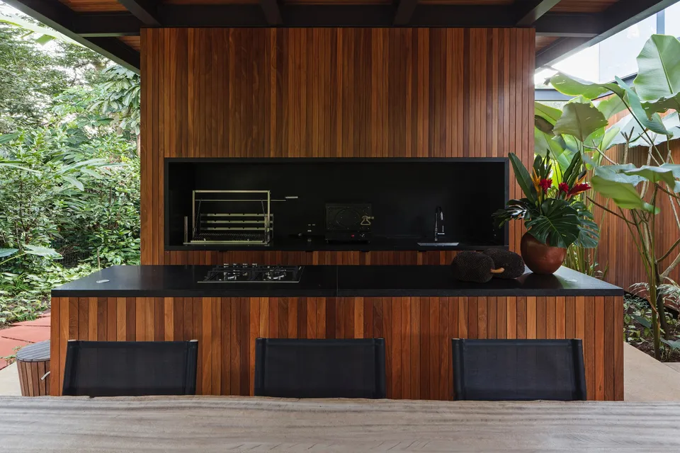 Vertical wood wall cladding behind a covered outdoor kitchen surrounded by greenery