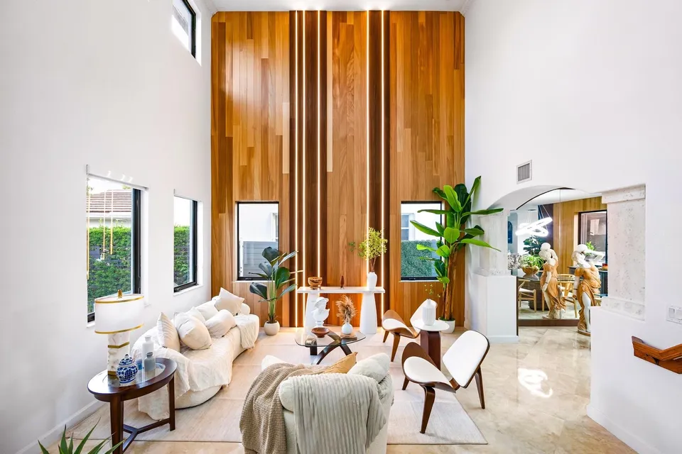 Double-height wood feature wall in a bright furnished living room