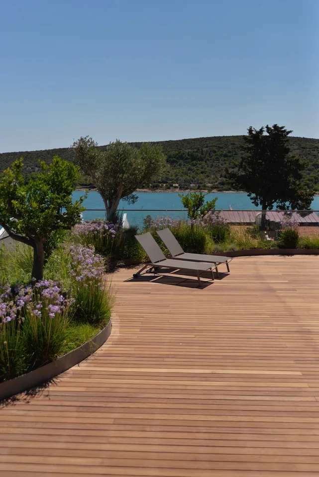 Wood decking with two lounge chairs, planting and a lake beyond