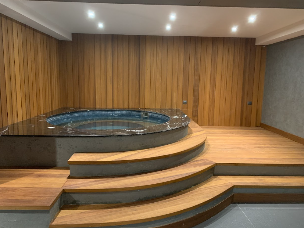 Wood cladding surrounds the walls of a built-in hot tub. 