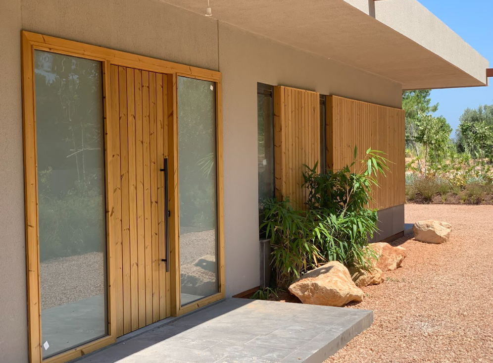 Thermally modified pine wood frames the exterior of a door and windows as cladding.